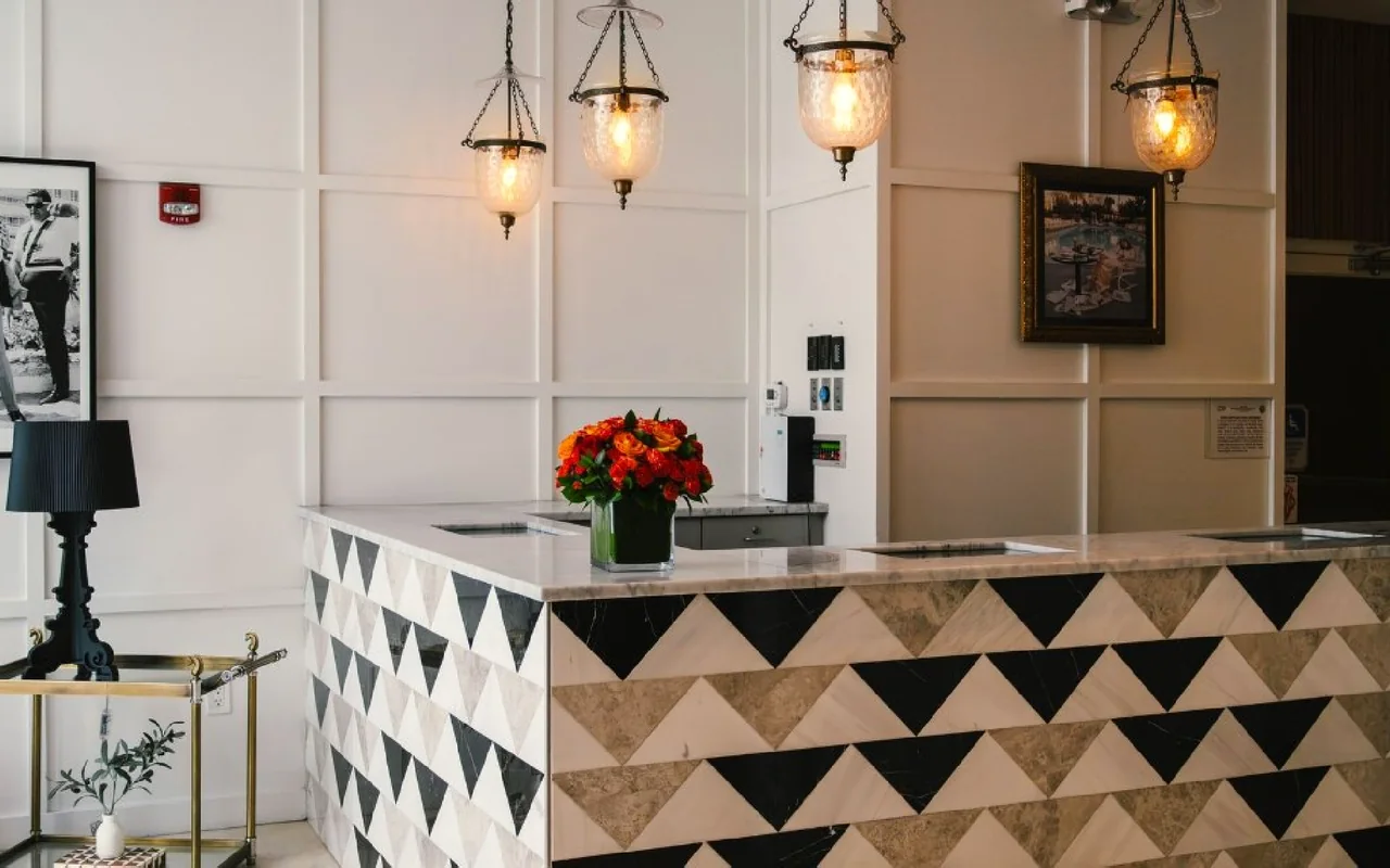 A hotel reception desk with pendant lights and a bouquet on the counter